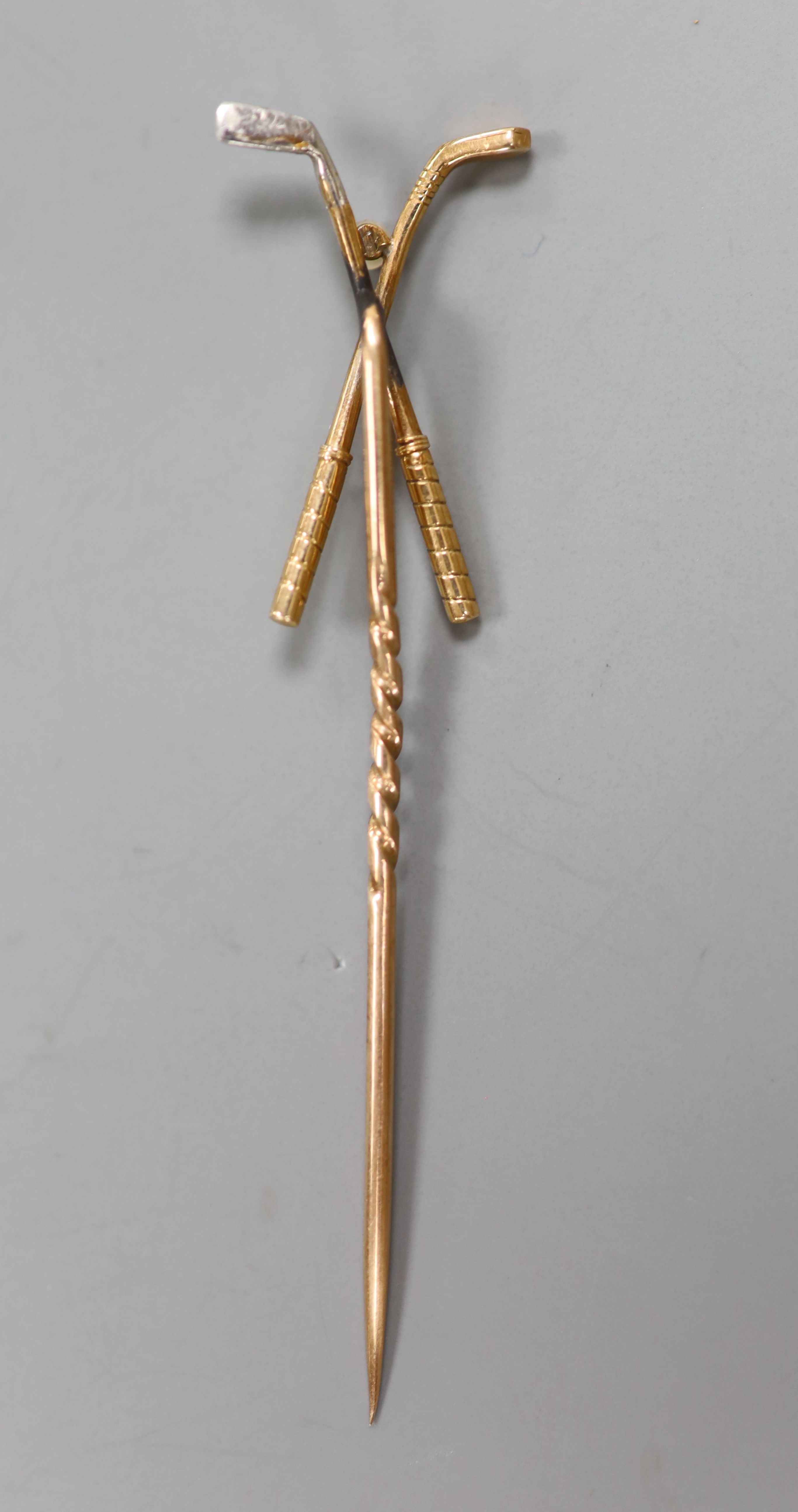 An early 20th century yellow metal and seed pearl set crossed golf clubs stick pin, 57mm, gross 1.6 grams.